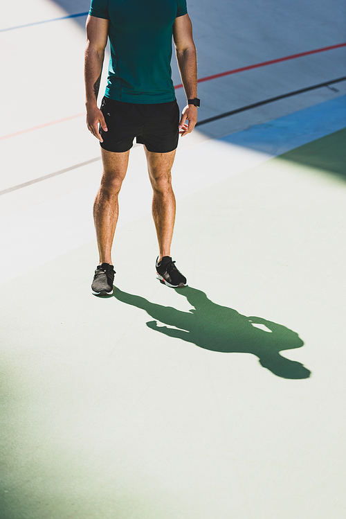 cropped view of sportsman standing in light place at stadium