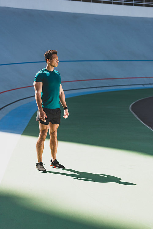 full length view of mixed race sportsman standing in light place at stadium