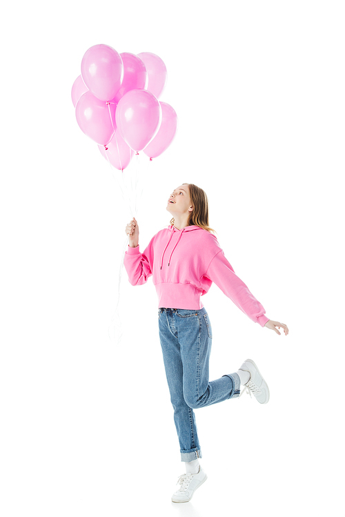 full length view of happy teenage girl looking at pink balloons isolated on white