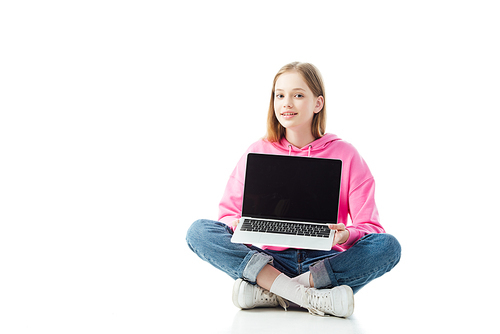 smiling teenage girl with crossed legs holding laptop with blank screen isolated on white, illustrative