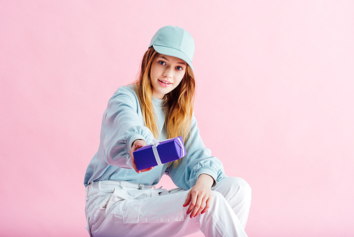 pretty teenage girl in cap isolated on pink