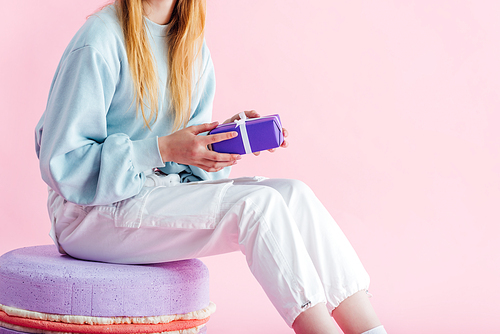 cropped view of teenage girl holding present isolated on pink