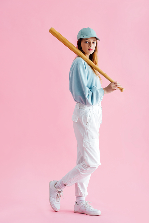 pretty teenage girl in cap holding baseball bat on pink