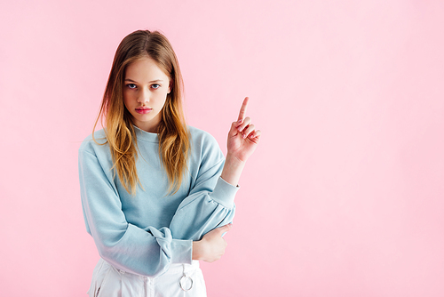 sad teenage girl pointing with finger isolated on pink