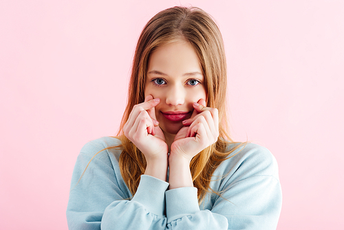 pretty teenage girl touching cheeks isolated on pink