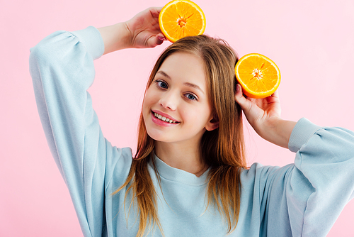 happy pretty teenage girl with orange halves on head isolated on pink