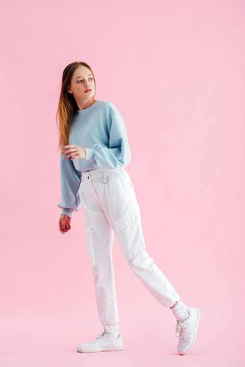 full length view of pretty teenage girl looking away on pink