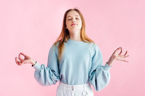 pretty teenage girl with closed eyes meditating isolated on pink