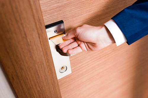cropped view of man using hotel card while opening door