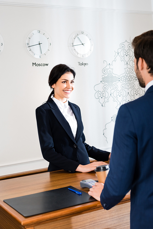 cropped view of man standing near happy receptionist in hotel