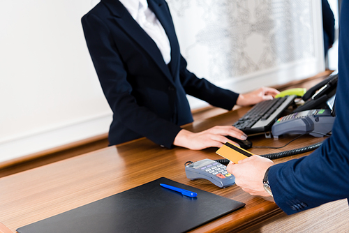 cropped view of man paying while holding credit card in hotel