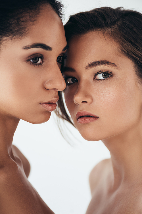 two attractive multiethnic young women looking away isolated on grey