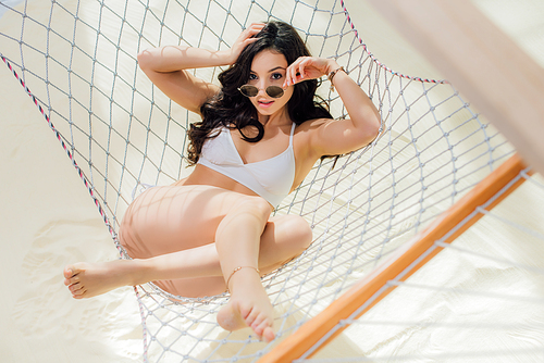 beautiful girl in bikini and sunglasses lying in hammock and  on beach