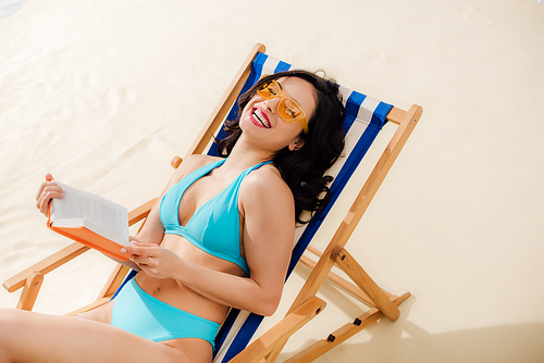 beautiful happy in 20대 여성 bikini lying on deck chair with book on beach