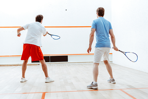 Back view of two sportsmen playing squash in four-walled court
