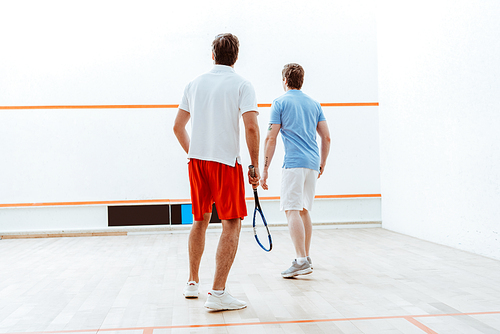 Back view of two sportsmen playing squash in four-walled court