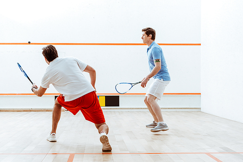 Full length view of two sportsmen playing squash in four-walled court