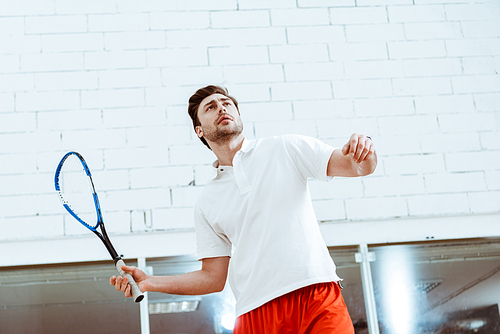 Sportsman in white polo shirt playing squash in four-walled court