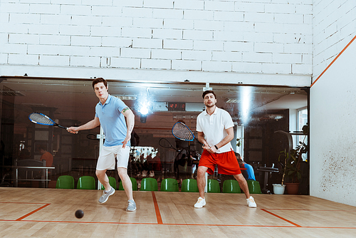 Full length view of two sportsmen playing squash in four-walled court