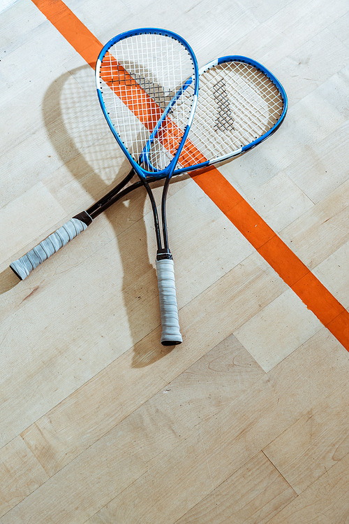 Two squash rackets on wooden floor in four-walled court