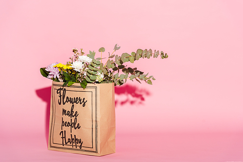 flowers and eucalyptus leaves in paper bag with flowers make people happy lettering on pink