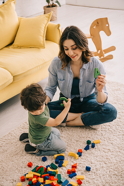 Mother and son playing with toy blocks on carpet