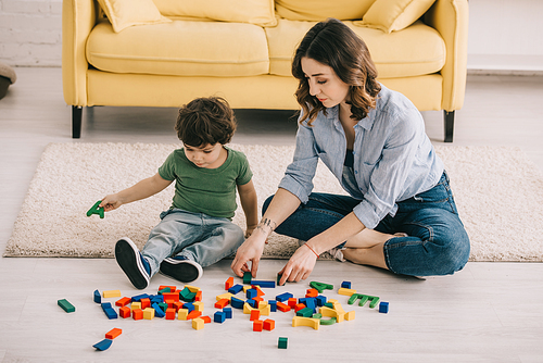 Mother and son playing with toy blocks on carpet
