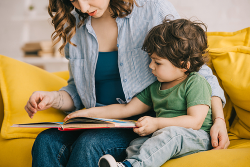 Cropped view of mother and son reading book together