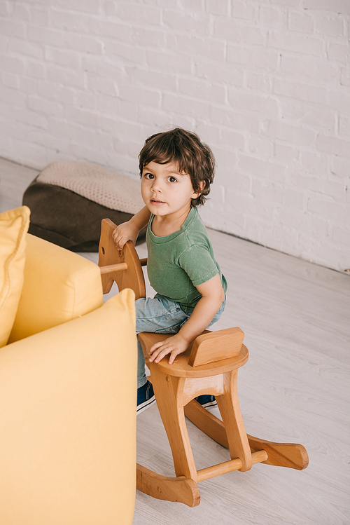 kid sitting on wooden rocking horse in living room