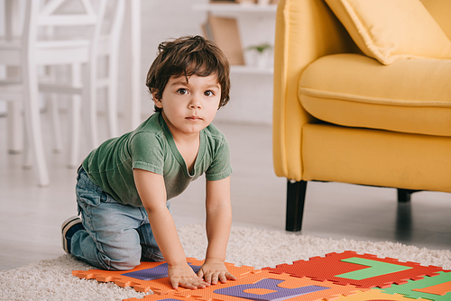 cute kid in green t-shirt playing with puzzle mat