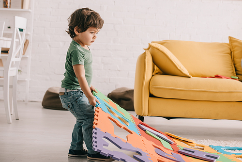 Full length view of kid in green t-shirt playing with puzzle mat