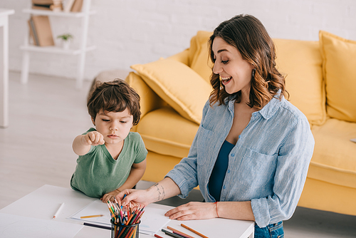 excited mother and son drawing with color pencils in living room