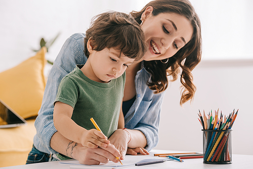 Mother and son drawing with color pencils in living room