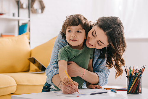 Mother and son drawing with color pencils in living room