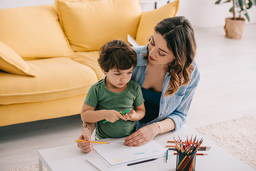 Mother and son drawing with color pencils in living room