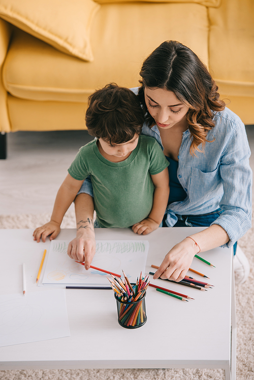 Mother and son drawing with color pencils in living room