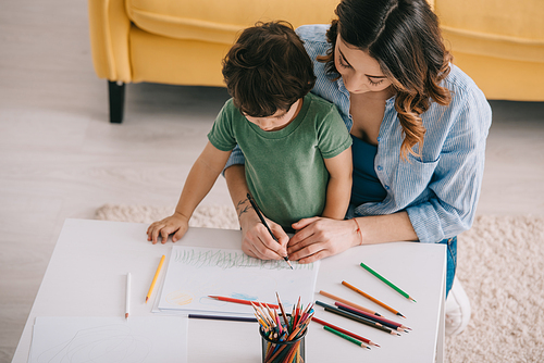 Mother and son drawing with color pencils in living room