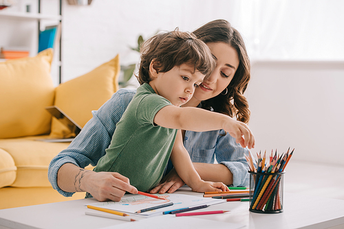 Mother and son drawing with color pencils in living room