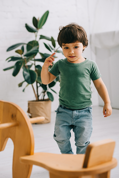 Toddler boy in green t-shirt and wooden rocking horse