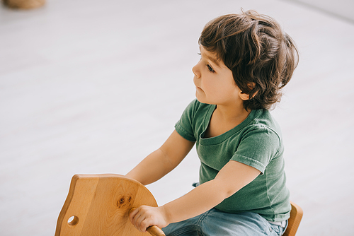 kid sitting on wooden rocking horse in living room