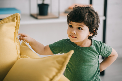 Curious child standing near yellow cushions in living room