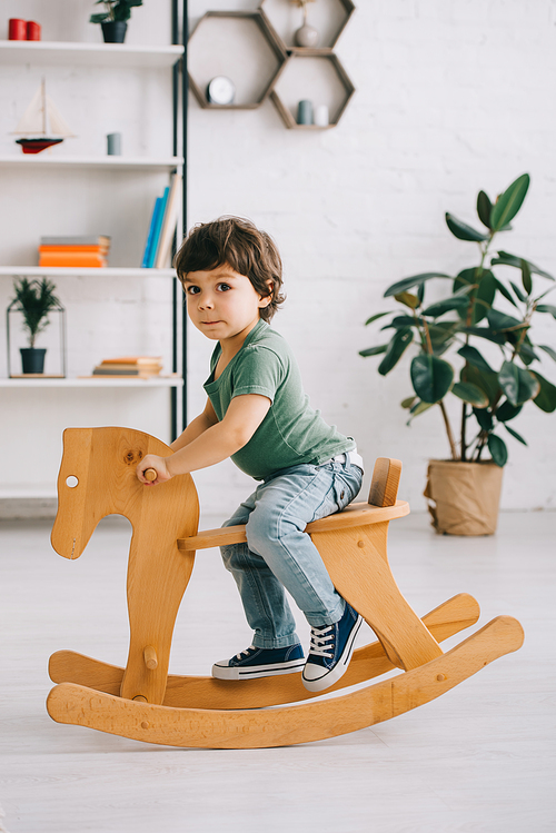 kid sitting on wooden rocking horse in living room