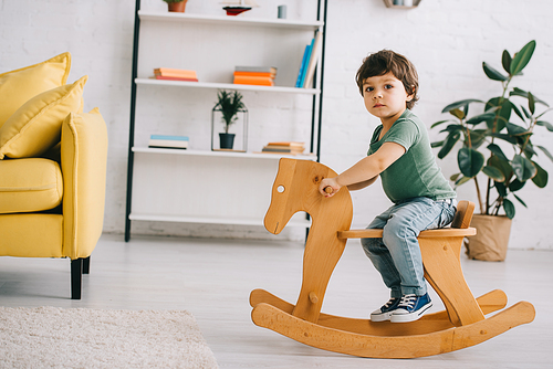 child sitting on wooden rocking horse in living room