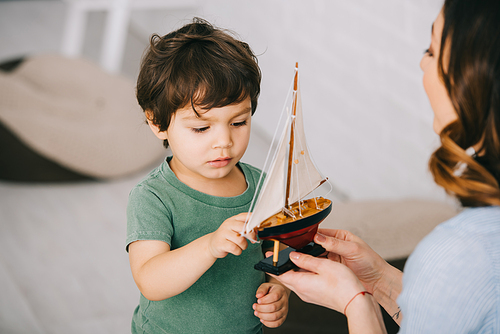 Cropped view of mother and little son with toy ship