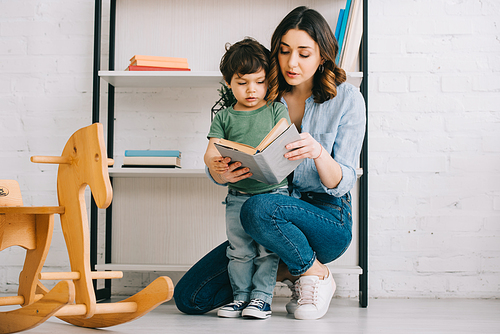 Mother and child reading book in living room