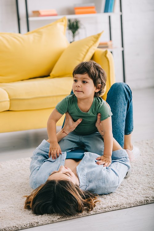 Happy mother and son playing on carpet in living room