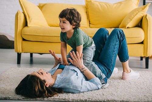 Happy mother and son playing on carpet in living room