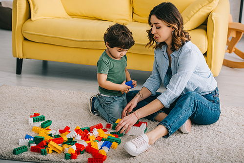 Mother and son playing with lego on carpet in living room