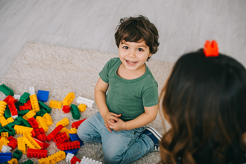 Mother and son playing with lego on carpet in living room