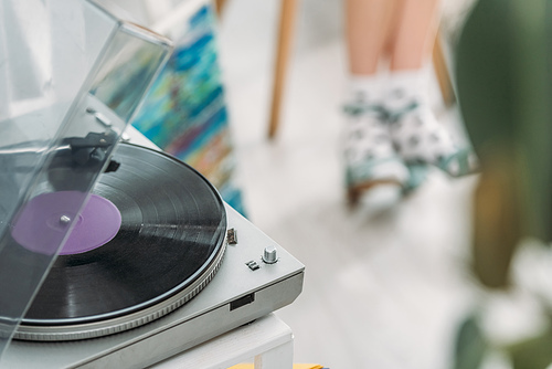 partial view of girl in dotted socks and record player with vinyl disc